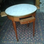 petite table Louis XVI, dite table bouillotte, en bois blond avec deux tiroirs et deux tirettes gainées de cuir. Plateau de marbre blanc.